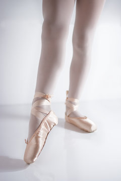 legs and feet with pink satin pointe shoes by a classical dancer posing