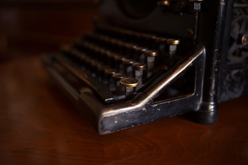 Selective focus on the keyboard key on an old black rustic typewriter on a desk in the office. The typewriter is much used but is still in good condition