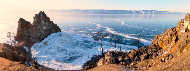Beautiful winter landscape of frozen Baikal Lake. Panoramic view of the natural landmark of Olkhon Island - the famous rock Shamanka and the Small Sea Strait at sunset