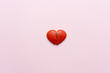 Red broken heart on pink background.