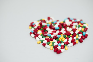 Many of hard gelatin capsules on the white background  and look likes heart pattern.