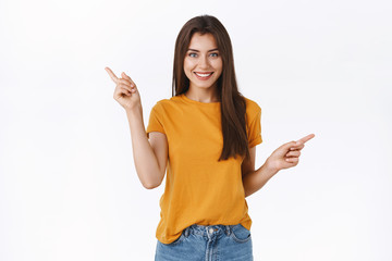 Carefree, happy smiling girl in yellow t-shirt shopping with confident relaxed expression, pointing...