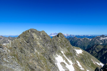 Fototapeta na wymiar Massive, sharp stony mountain range of Schladming Alps, Austria. The mountain has a pyramid shape, it is partially overgrown with green bushes. Dangerous mountain climbing.Clear and beautiful day.