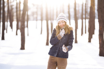 Happy young woman plays with a snow in sunny winter day. Girl enjoys winter, frosty day.  Playing with snow on winter holidays, a woman throws white, loose snow into the air. Walk in winter forest.