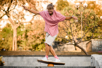 Naklejka premium Boy balancing on the balance board on the concrete steps in the park