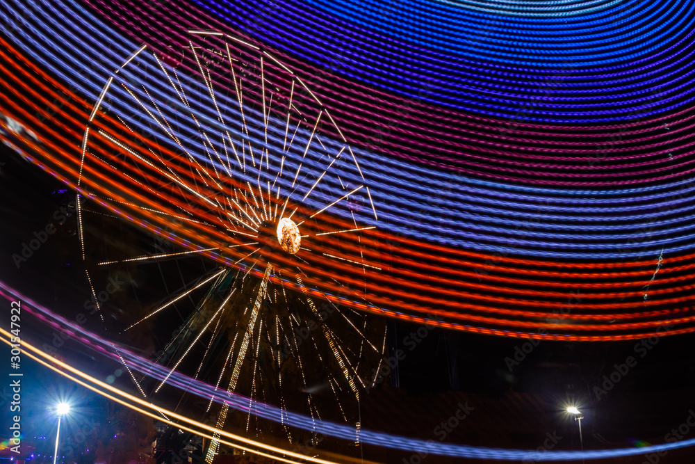 Poster Two rides in motion in amusement park, night illumination. Long exposure.