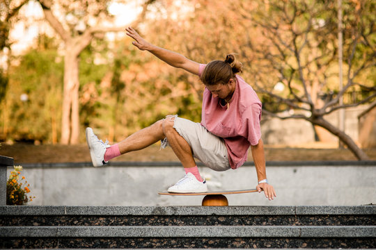 Man balancing squat on the balance board on the concrete steps in the park