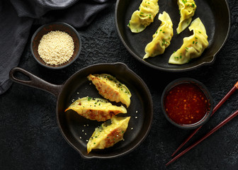 Steamed and Fried yaki Gyoza served on cast iron skillet, pan with sweet chilli sauce and sesame seeds
