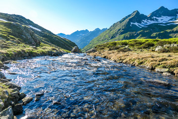 A serene view on snowy mountain from a small stream's side. The stream starts it's long way to the...