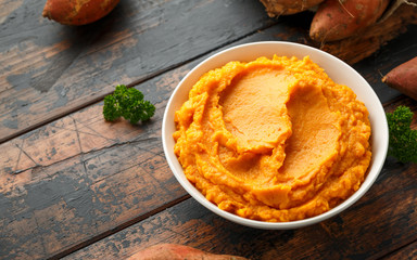 Mashed Sweet Potatoes in white bowl on wooden rustic table. Healthy food