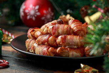 Christmas Pigs in blankets, sausages wrapped in bacon with decoration, gifts, green tree branch on...