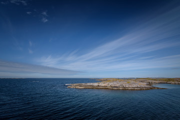 Ocean and sky are blue with lines in the clouds ocean view