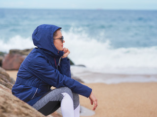 Portrait of a beautiful woman with a hood on a cloudy day at the beach