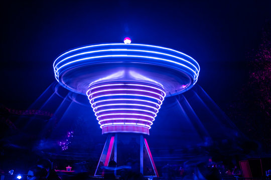 A blurry colorful carousel in motion at the amusement park, night illumination. Long exposure.