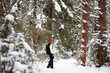 A man travels with a backpack. Winter hike in the forest. Tourist on a walk in the winter in the park.