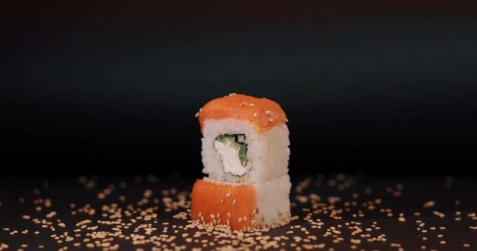 Eating salmon sushi with asian chopsticks, macro video, black background