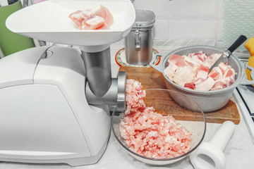 A piece of meat is ready for chopping. Cook makes minced fresh meat in a meat grinder