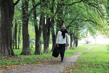 Fototapeta premium A young man in glasses walks in the park with an umbrella during the rain.