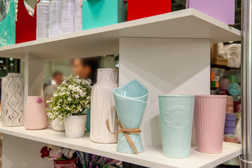A pitcher, a set of clean dishes and vases for flowers on white shelves