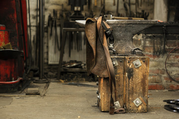 Anvil, hammer and leather apron in smithy