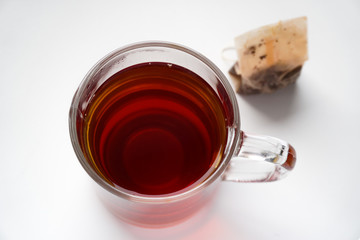 Cup of tea and used tea bag on white background