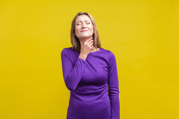 Throat pain. Portrait of unhappy ill woman in elegant tight purple dress touching her neck,...