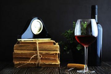 A glass of red dry wine on the table. Dark bottle and glass of wine.