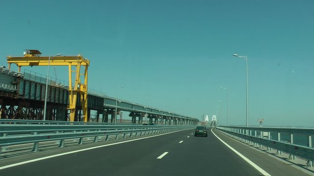 the car goes along the Crimean bridge, the railway bridge under construction on the left