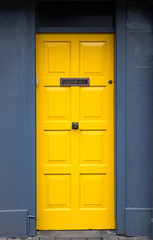 Obraz na płótnie Canvas Vibrant yellow door on dark grey wall background