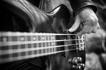 Rock guitarist outdoor. A musician with a bass guitar in a leather suit. Metalist with a guitar on...