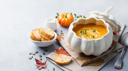 Pumpkin and carrot cream soup in bowl on grey stone background. Copy space.