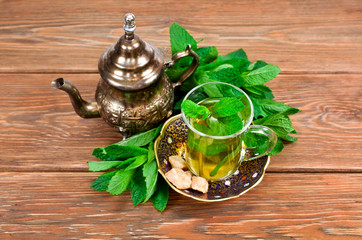 Moroccan tea with green mint leaves on a wooden background
