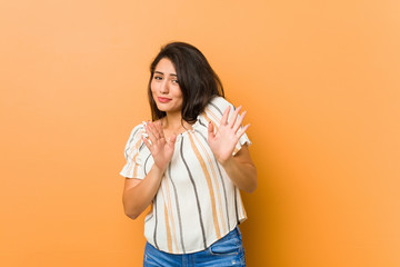 Young curvy woman rejecting someone showing a gesture of disgust.