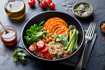 Healthy vegetarian salad. Roasted pumpkin, quinoa, tomatoes, green salad. Buddha bowl. Slate background. Close up. - 301558560