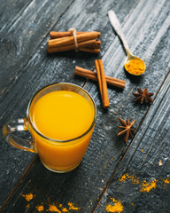 turmeric spicy tea in a glass mug on a dark wooden table