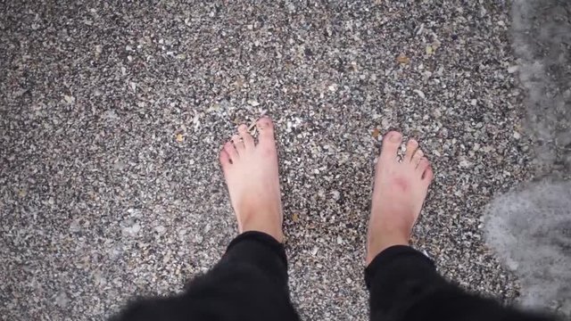 Women's feet are on a sandy beach.Women's feet washed by ocean waves and buries them in the sand.