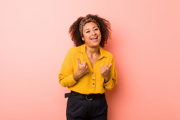 Young african american woman against a pink background raising both thumbs up, smiling and confident.