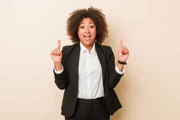 Young business african american woman indicates with both fore fingers up showing a blank space.