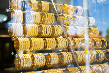 Showcase with gold womens bracelets. Many beautiful women's bracelets made of precious metals hang on the window.