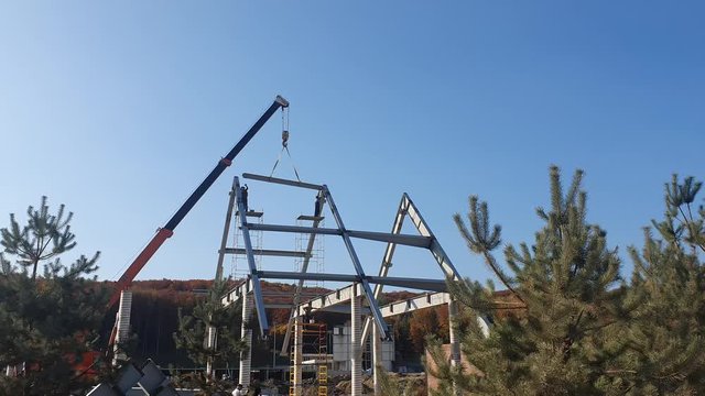 Installation of a roof and a framework from a metal construction. Workers mount the roof.