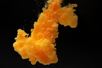 Abstract flowing liquid or orange color ink in water on a black background. It looks like smoke or...