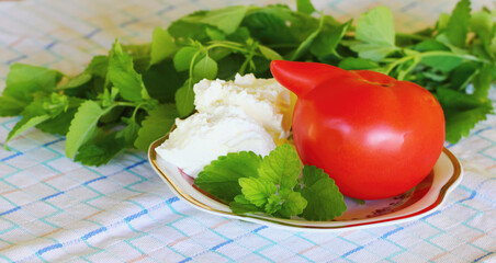 Sour cream ,mint and tomatoes on table