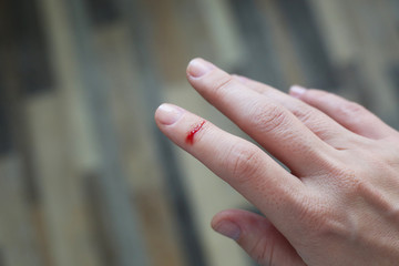 Finger with blood drop. Injured by sharp knife.