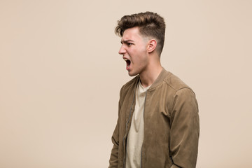 Young caucasian man wearing a brown jacket shouting towards a copy space