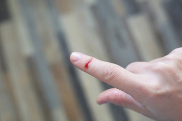 Finger with blood drop. Injured by sharp knife.