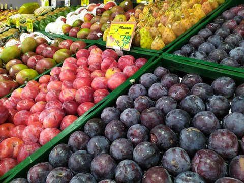 Frisches Obst am Marktstand eines Obsthändlers lädt zum gesunden Essen und Einkaufen ein mit Ananas, Mango, Granatapfel, Birnen, Pflaumen und anderen leckeren Früchten