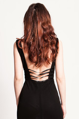 elegant woman with long red hair in black dress back wiev  studio shot