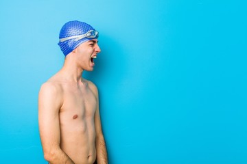 Young swimmer man shouting towards a copy space