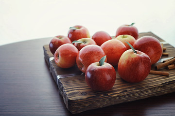 Fresh apples on a wooden board. Harvest of red apples. Fruits and cinnamon on the table.
