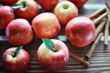 Fresh apples on a wooden board. Harvest of red apples. Fruits and cinnamon on the table.